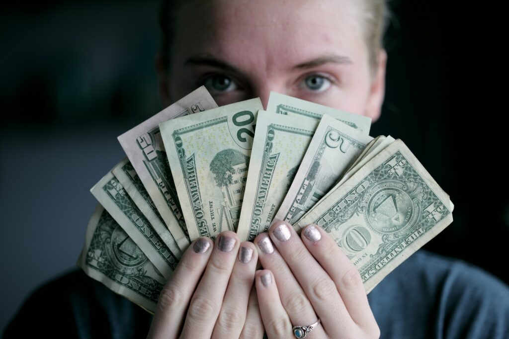 Mulher segurando o dinheiro para investir na bolsa de valores.