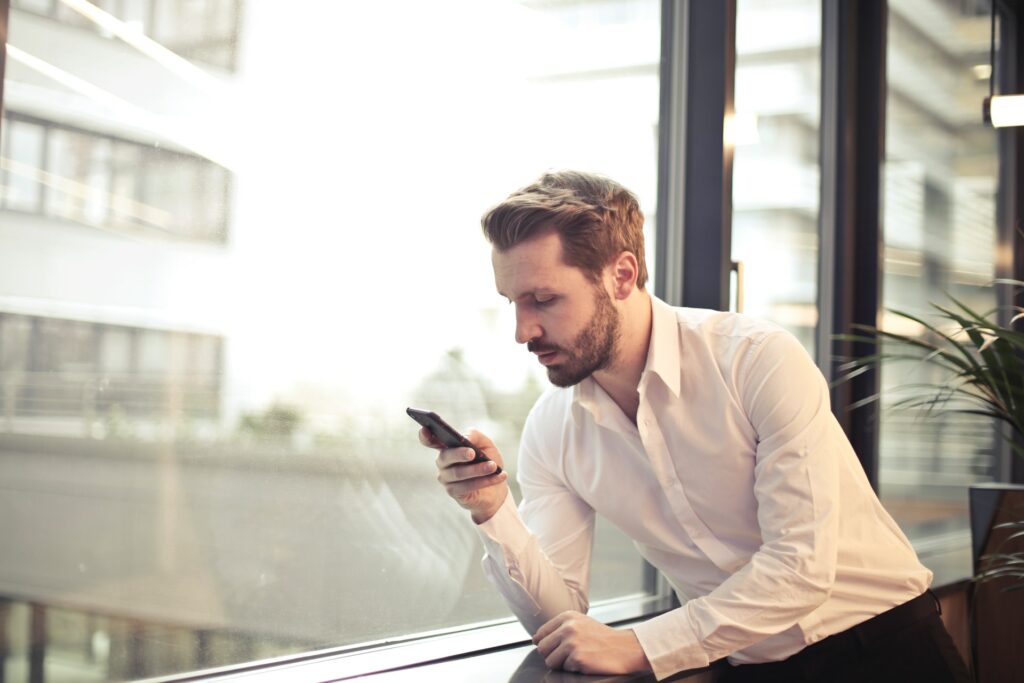 Homem branco segurando o celular em busca do melhor banco digital.